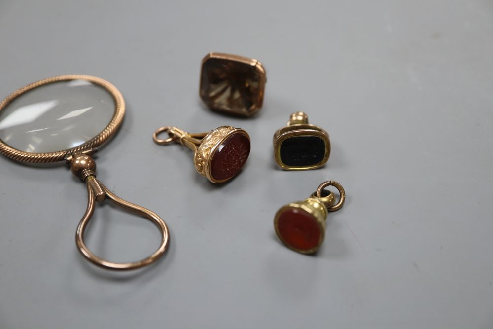 A 9ct mounted smoky quartz fob seal, 28mm, two yellow metal overlaid fob seals, a gilt fob seal and a magnifying glass.